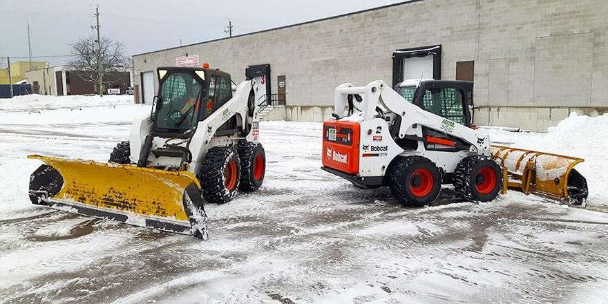 two snow plows on cleared parking lot