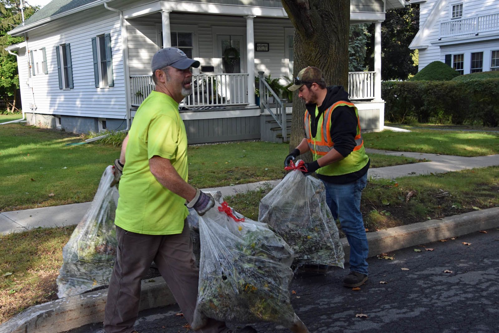 men taking away bags of leaves from a home