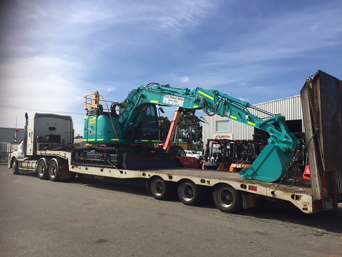 A large excavator is being transported on a flatbed trailer.