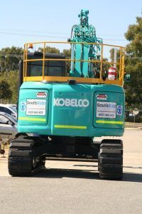 A blue kobelco excavator is parked in a parking lot.