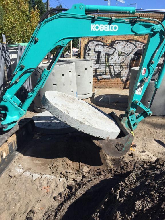 A kobelco excavator is digging a hole in the ground
