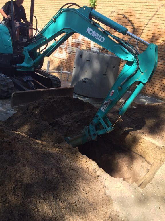 A kobelco excavator is digging a hole in the ground