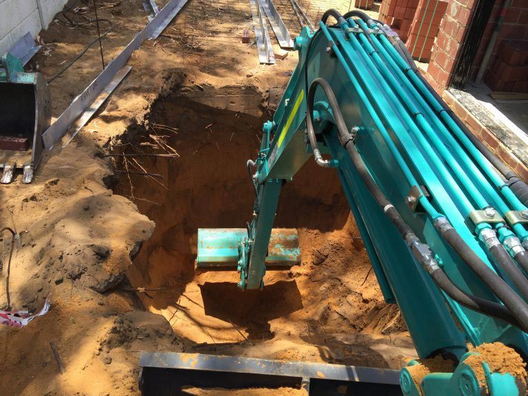 A blue excavator is digging a hole in the ground