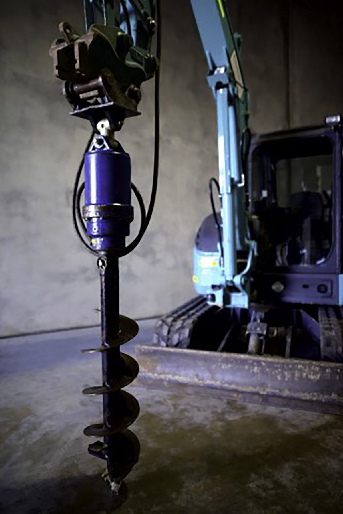 A blue excavator with a large drill attached to it.