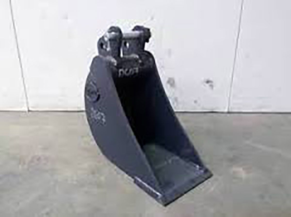 A black bucket is sitting on a concrete floor in front of a white wall.