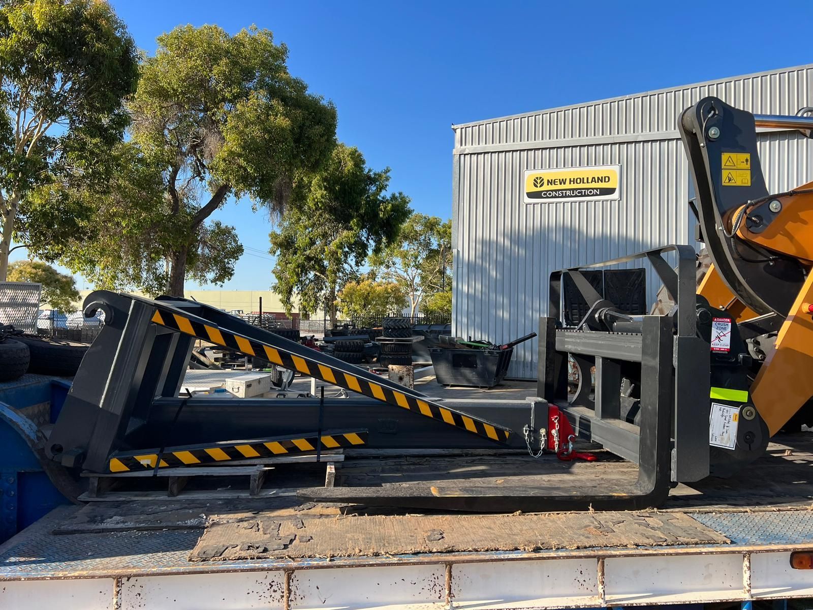 A large piece of equipment is sitting on top of a truck in front of a building.