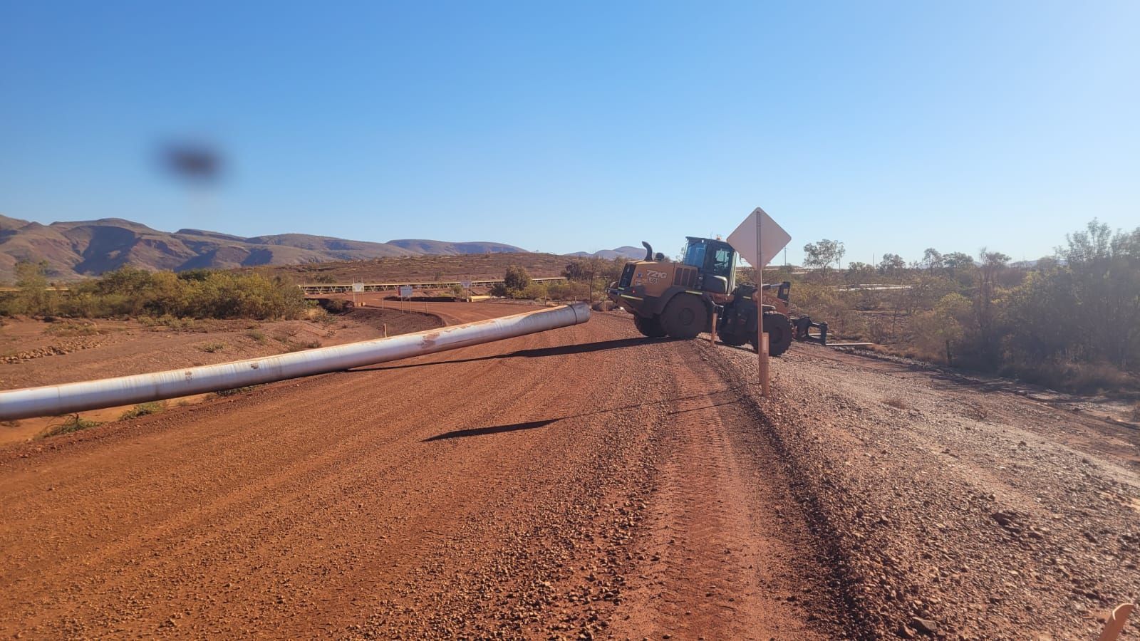 A tractor is driving down a dirt road in the desert