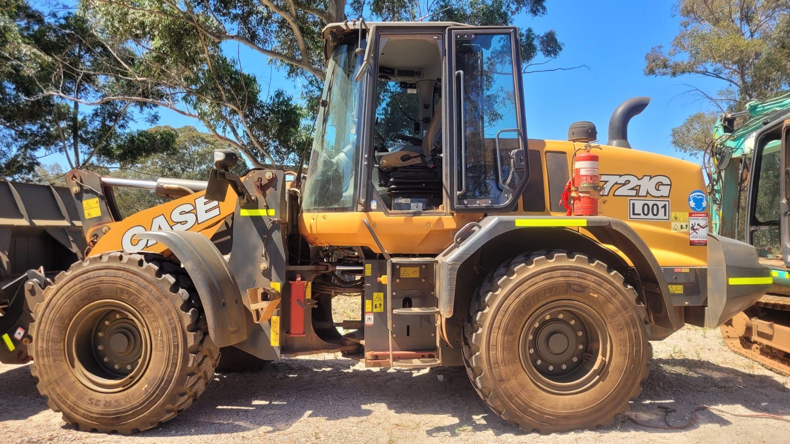 A yellow case wheel loader is parked on a dirt road.