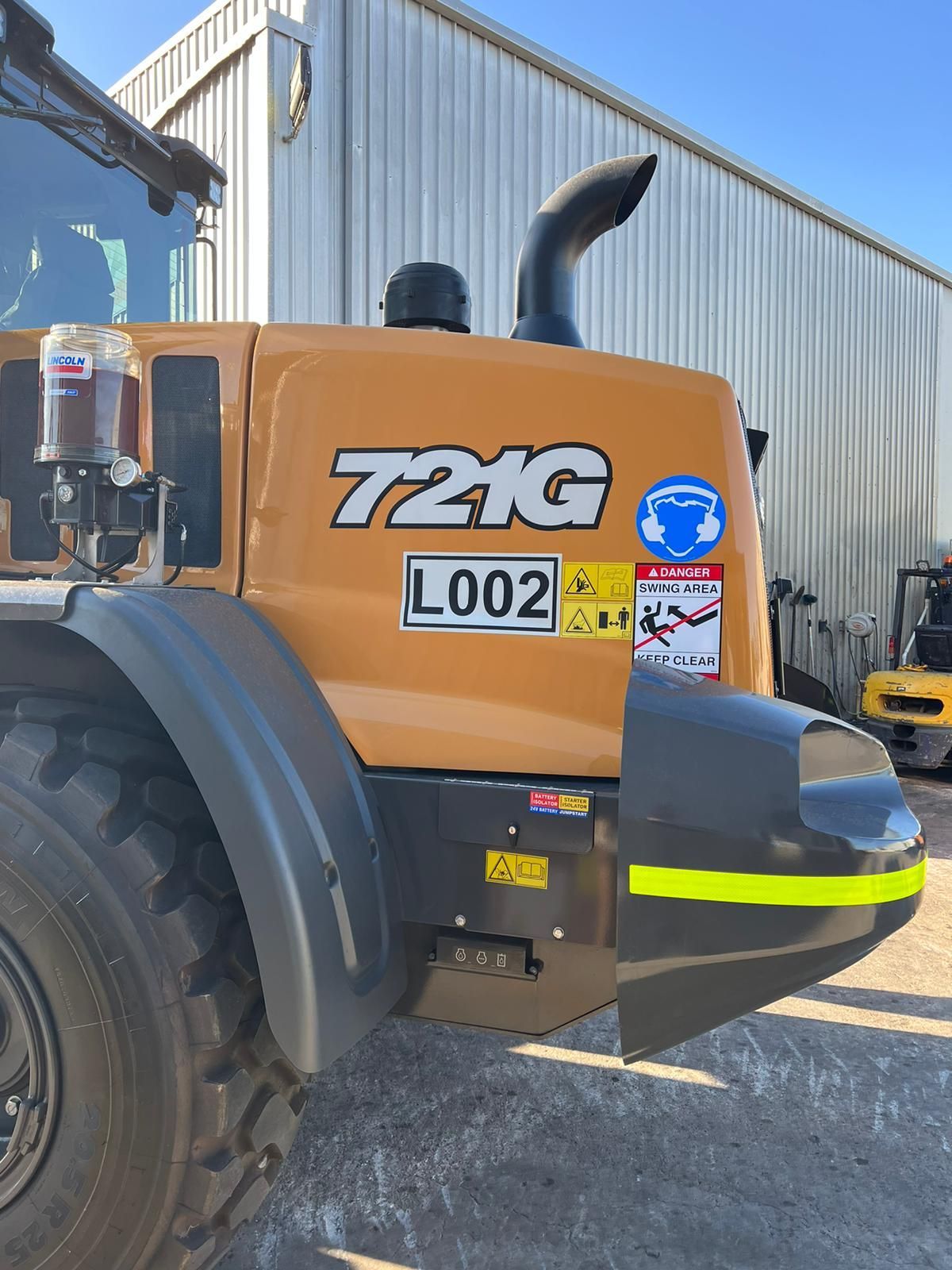 A tractor with a license plate that says 72kg is parked in front of a building.