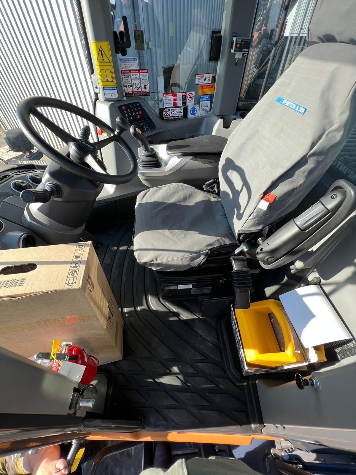 The inside of a tractor with a steering wheel and seats.
