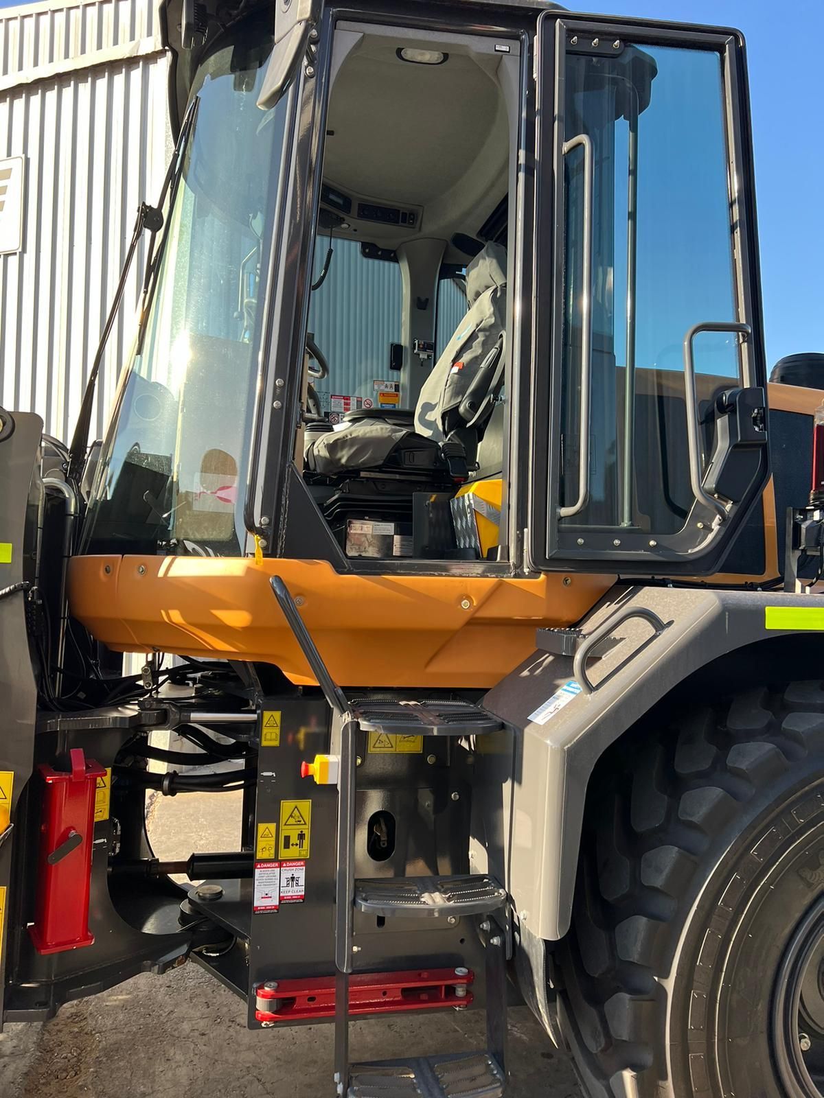 A yellow and black tractor is parked in front of a building.