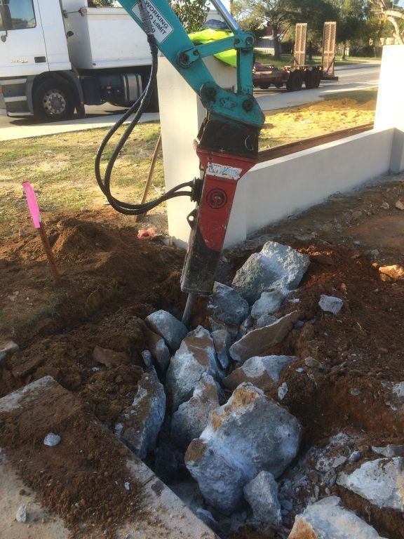 A machine is breaking rocks in a hole in the ground.
