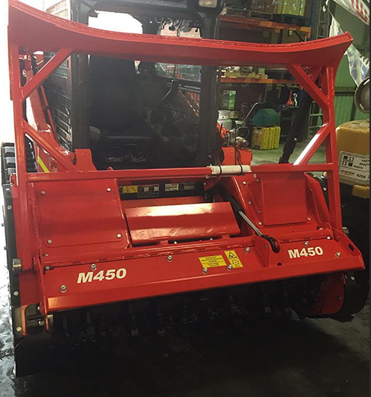 A red m450 tractor is parked in a garage