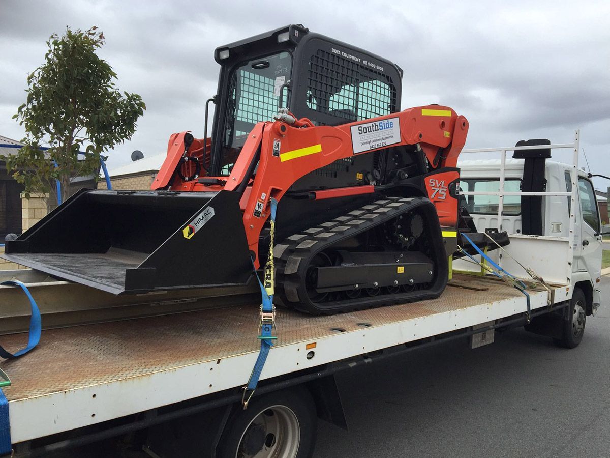 A bulldozer is sitting on top of a tow truck.