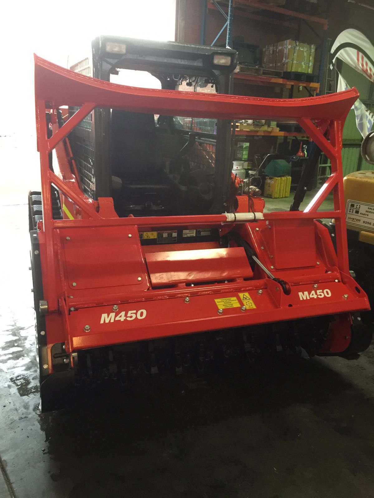 A red m450 tractor is parked in a garage