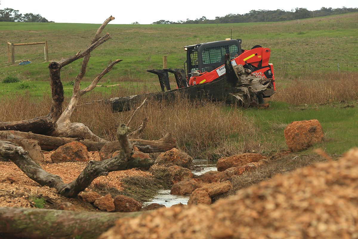 A tractor is cutting down a tree in a field.
