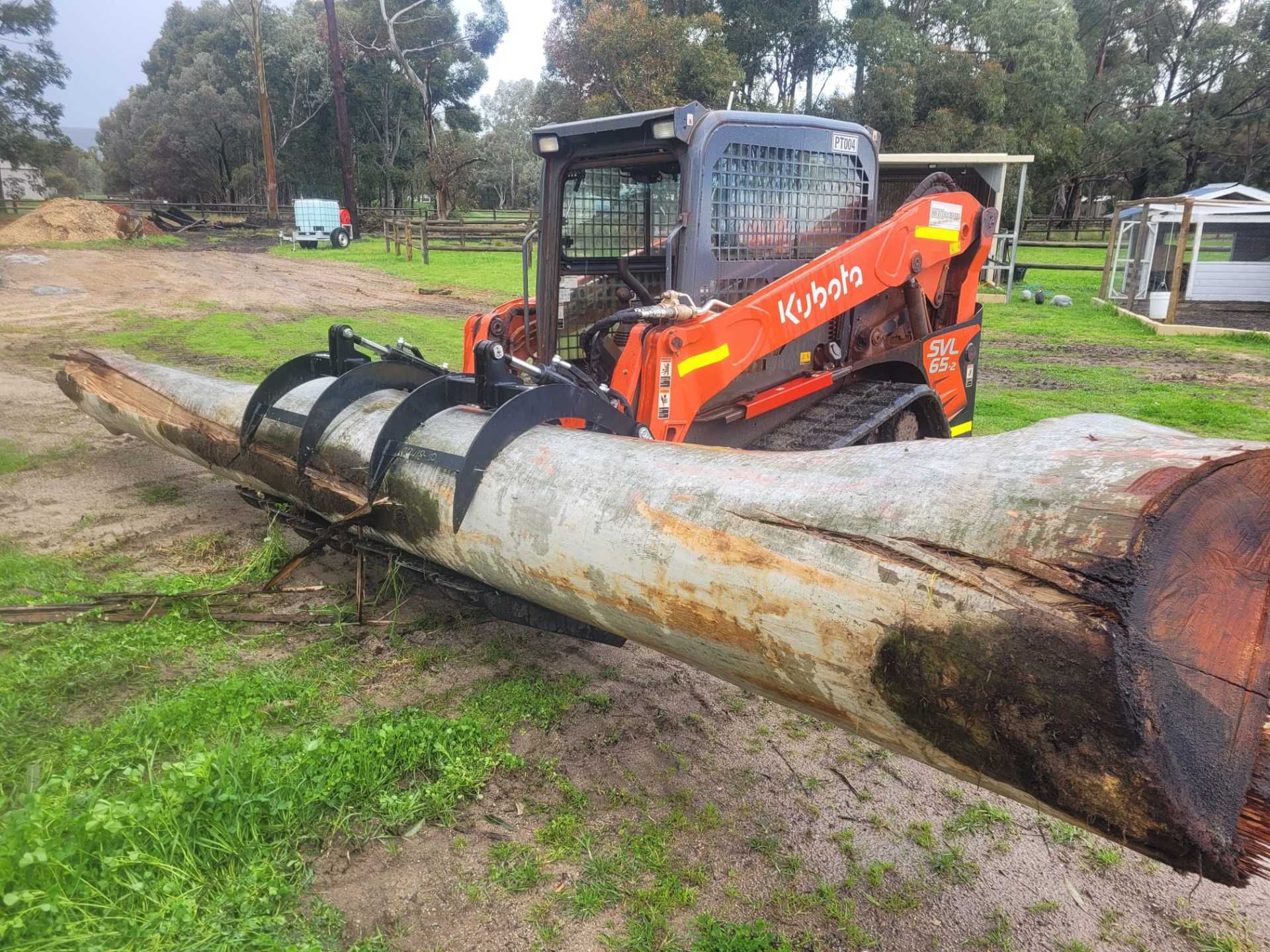 A bulldozer is carrying a large log in a field.