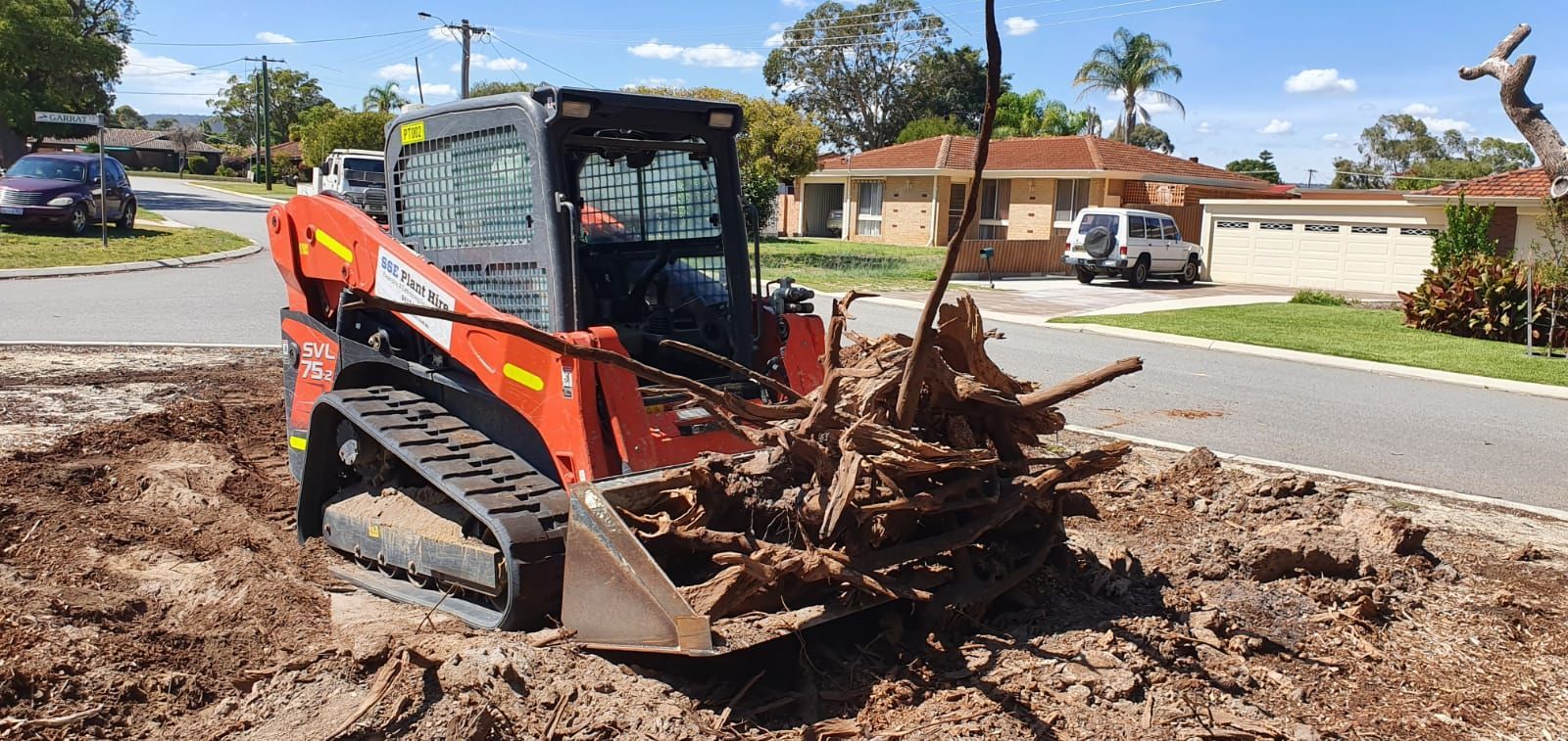 A bulldozer is sitting in the dirt next to a pile of logs.