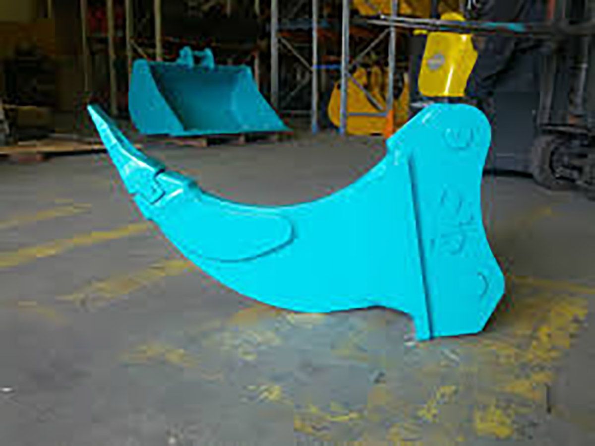 A blue excavator bucket is sitting on the ground in a warehouse.