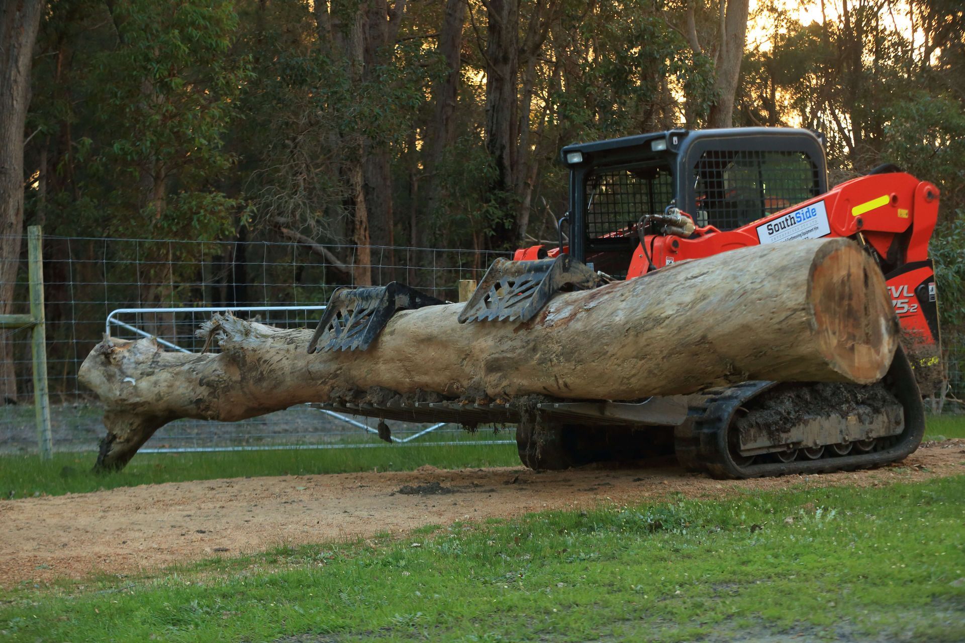 A large log is being lifted by a bulldozer.