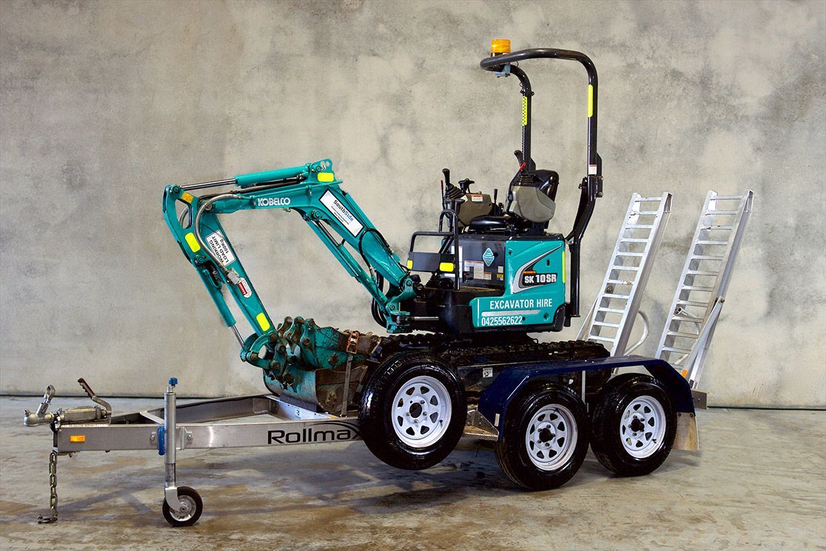 A small excavator is parked on a trailer.