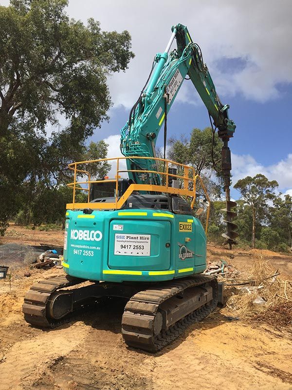 A blue and yellow excavator is digging a hole in the ground.