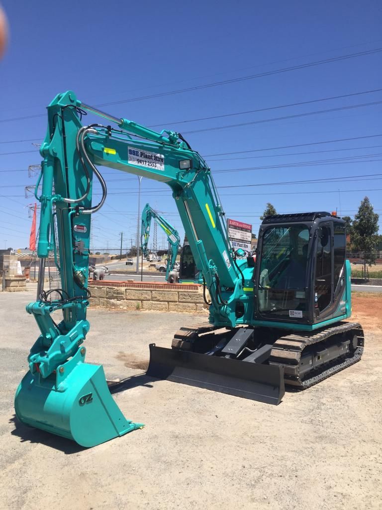 A green excavator is parked on the side of the road.
