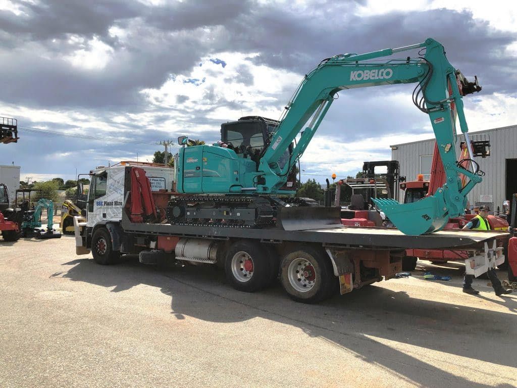 A large excavator is sitting on top of a flatbed truck.