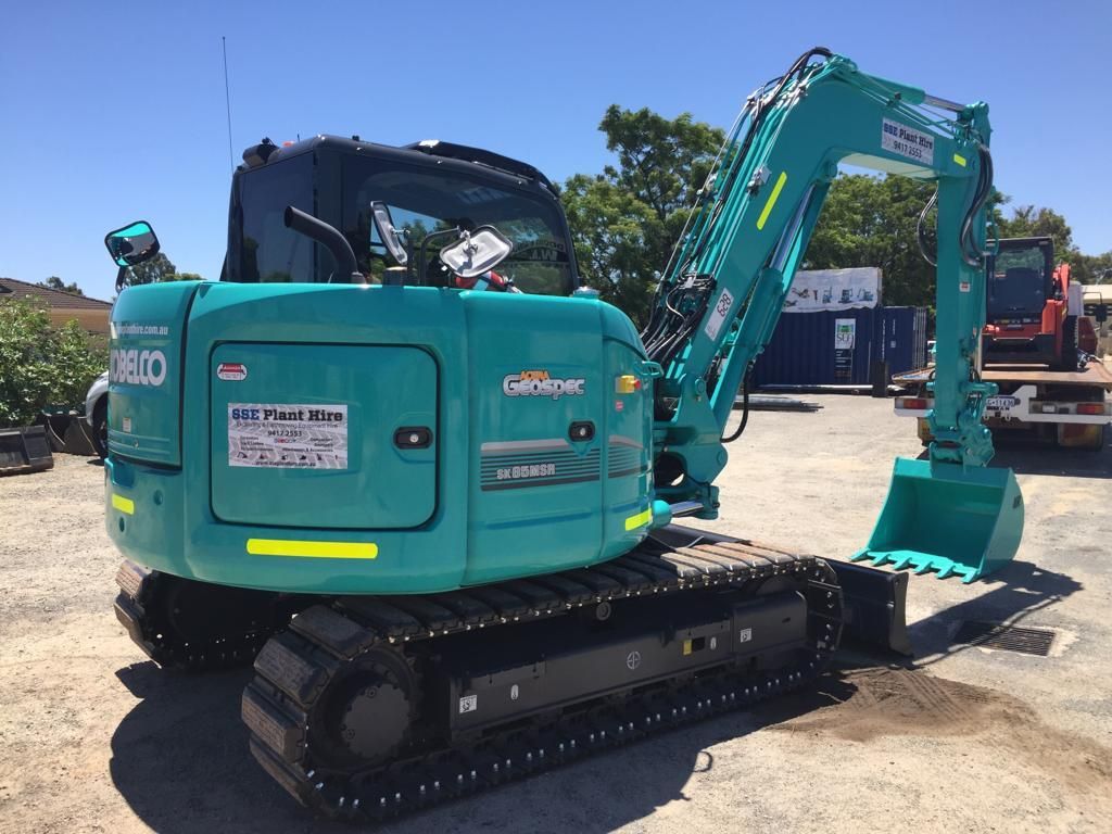 A blue excavator is parked in a parking lot.