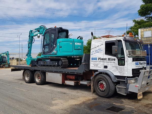 A tow truck with a blue excavator on the back of it.