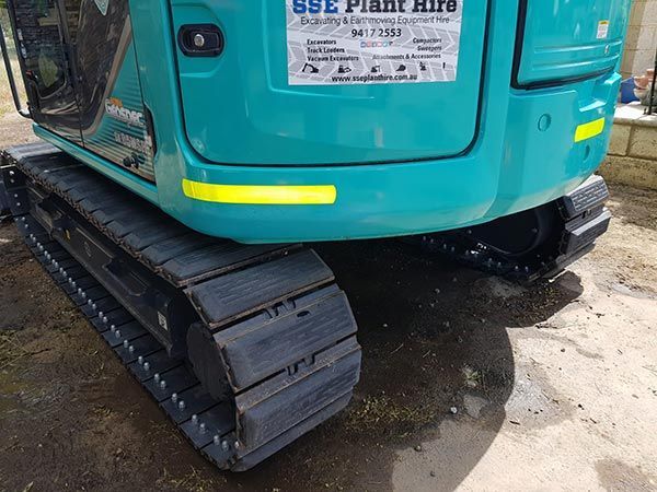 A blue excavator is parked on the side of the road.