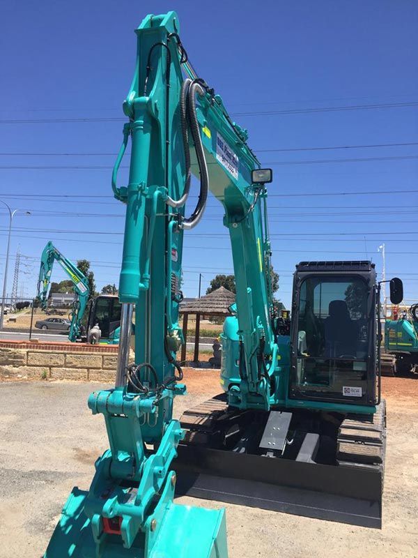 A large green excavator is parked in a parking lot.