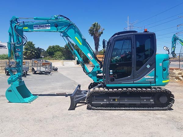 A small blue excavator is parked in a parking lot.