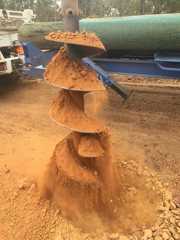 A drill bit is being used to dig a hole in the ground.