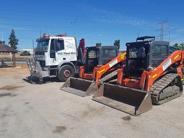 Two bulldozers are parked next to each other in a parking lot.