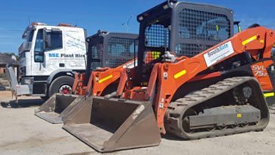 Two bulldozers are parked next to each other on a dirt road.