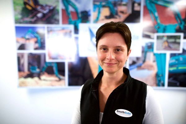 A woman wearing a black vest with a white logo on it