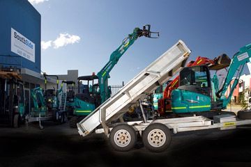A dump truck is on a trailer with a crane attached to it.