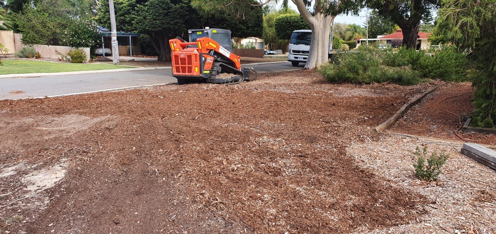 A large pile of mulch is being spread on the ground in a yard.