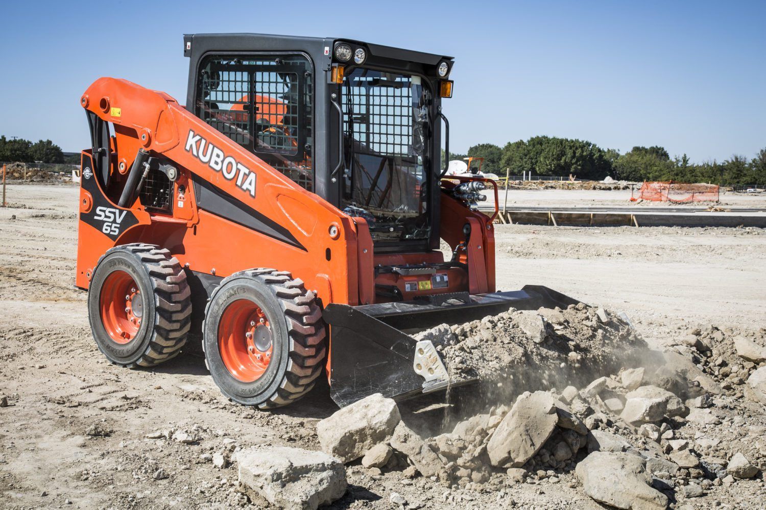 A kubota skid steer is moving rocks on a construction site.