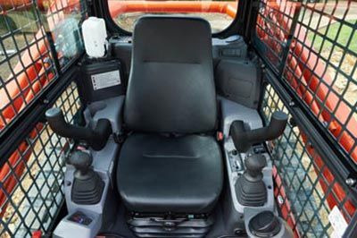 The inside of a bulldozer with a black seat and controls.
