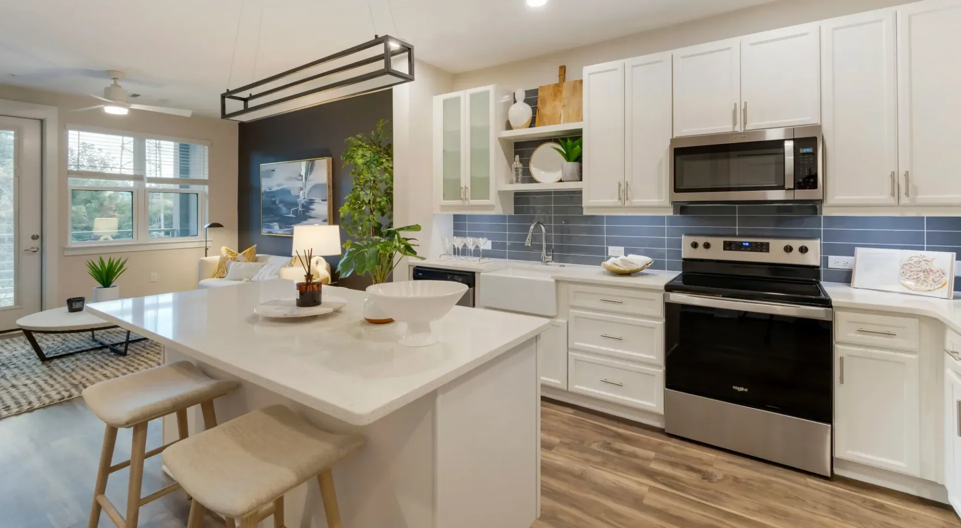 Bright open-plan kitchen with white cabinets, stainless steel appliances, and a large island.
