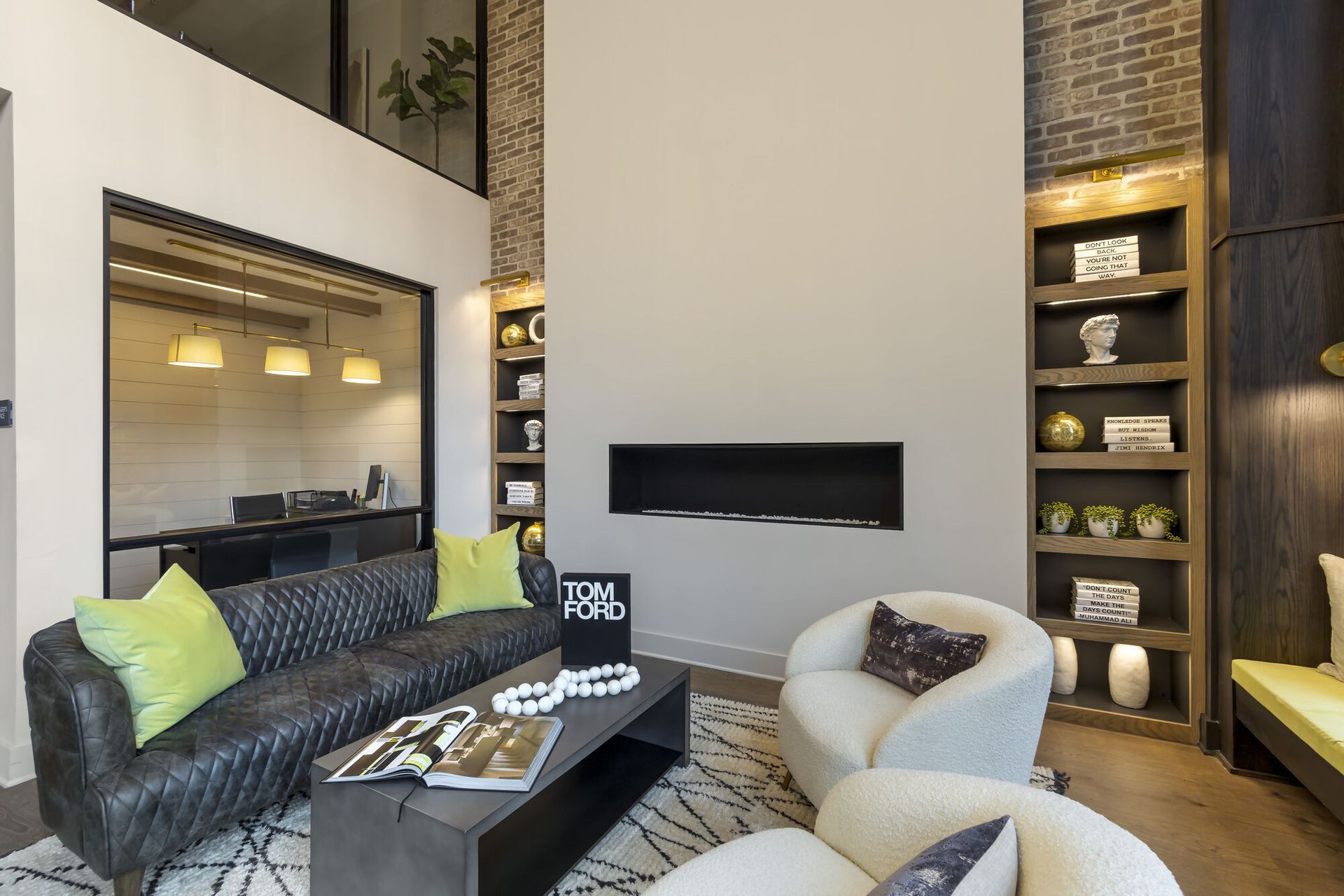 Modern resident lounge with a black quilted sofa, white chairs, a fireplace, and built-in shelves.