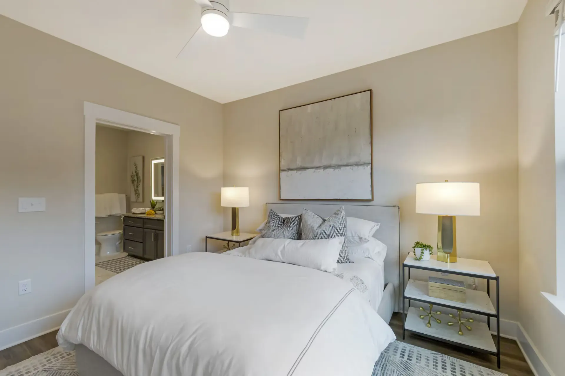 Bedroom with a made bed, two nightstands, lamps, and a doorway to an adjacent bathroom.
