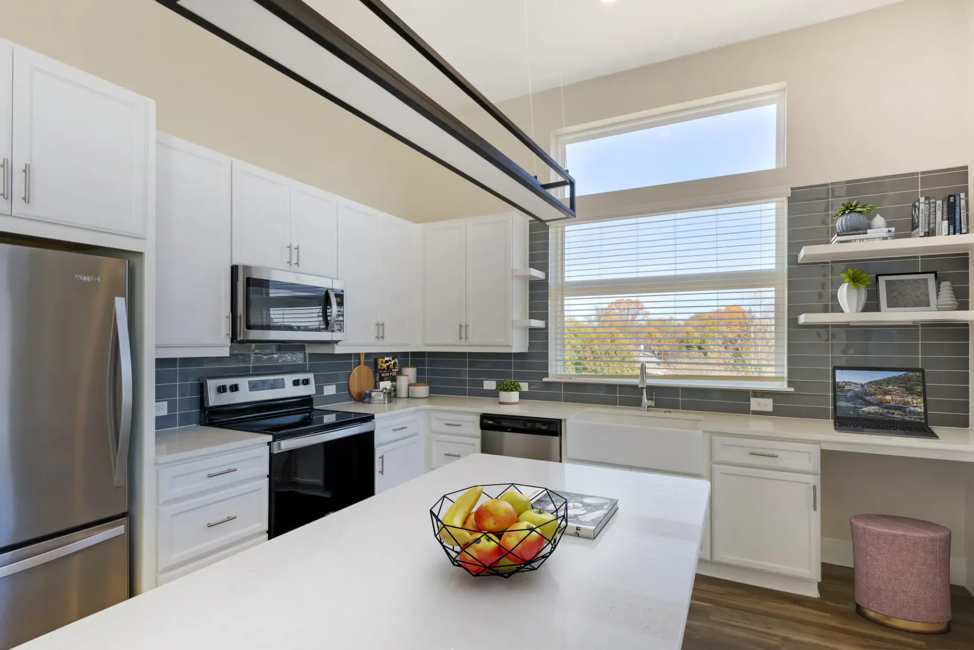 Bright modern kitchen with white cabinets, stainless steel appliances, an island, and a large window.