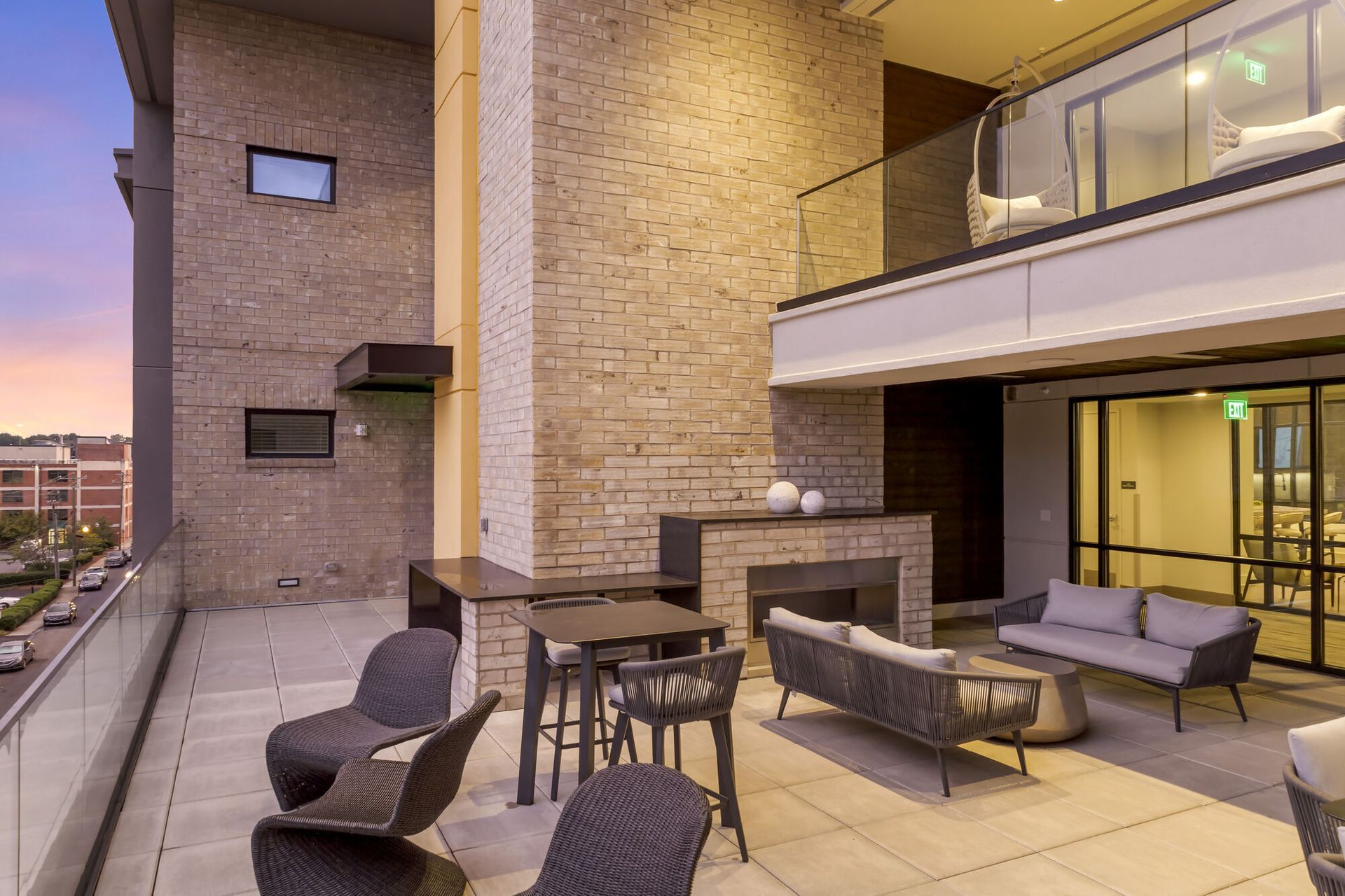 Outdoor residential terrace with brick walls, glass railing, and contemporary seating.