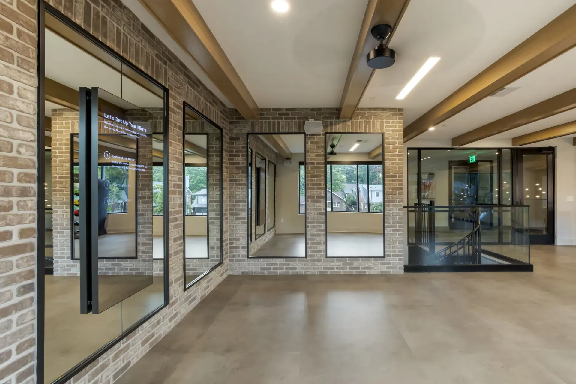 Interior community amenity space with brick walls, large mirrors, and a glass railing by a stairwell.