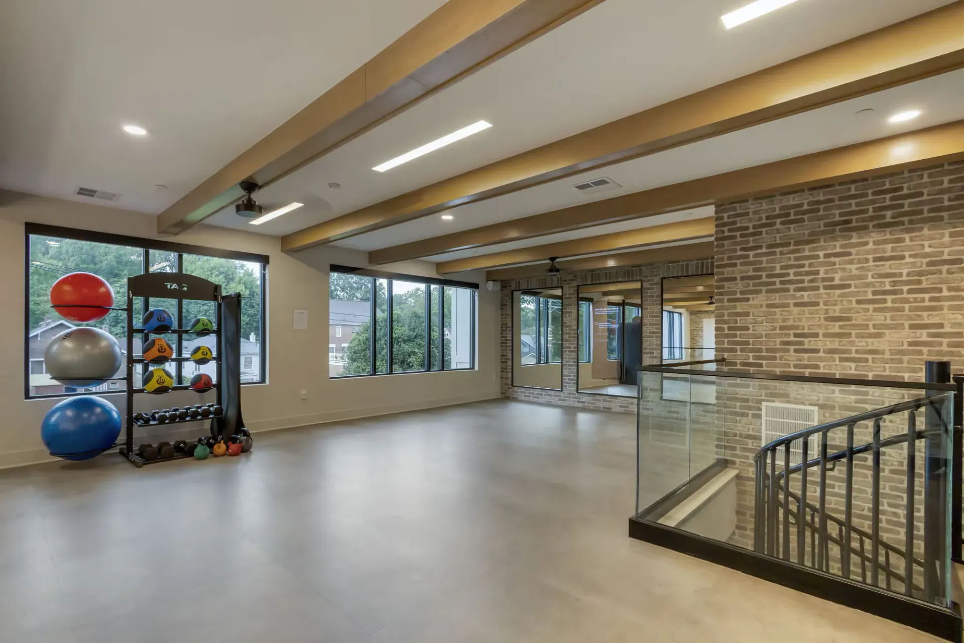 Interior community gym with free weights, medicine balls, and large windows.