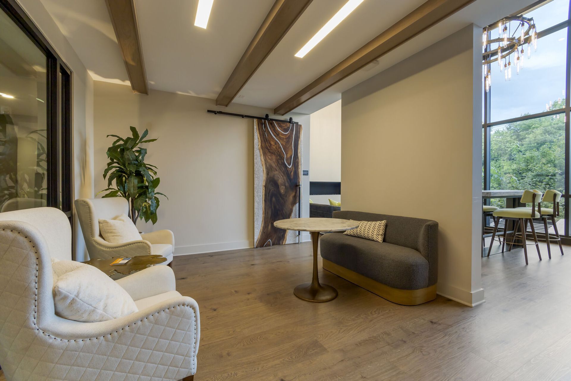 Interior community lounge with beige armchairs, a gray sofa, and a round table.