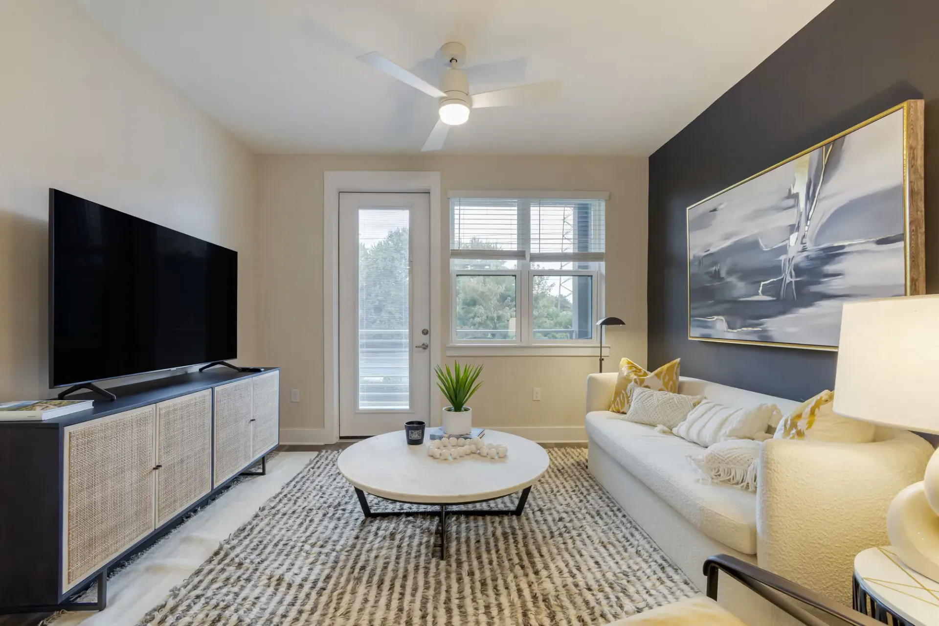Living room with a white sofa, coffee table, TV, and large window.